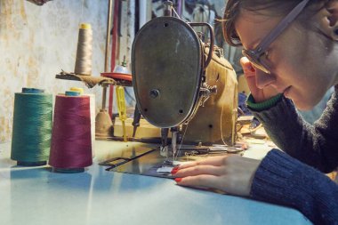 Evde retro dikiş makinesi kullanan bir kadın terzi, hobi konsepti..