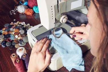 Evde retro dikiş makinesi kullanan bir kadın terzi, hobi konsepti..