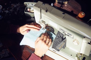Evde retro dikiş makinesi kullanan bir kadın terzi, hobi konsepti..