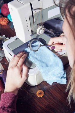 Evde retro dikiş makinesi kullanan bir kadın terzi, hobi konsepti..