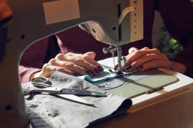 Evde retro dikiş makinesi kullanan bir kadın terzi, hobi konsepti..