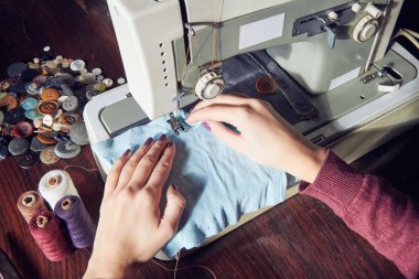 Evde retro dikiş makinesi kullanan bir kadın terzi, hobi konsepti..