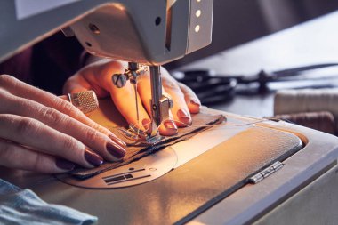 Evde retro dikiş makinesi kullanan bir kadın terzi, hobi konsepti..