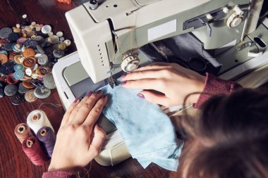 Evde retro dikiş makinesi kullanan bir kadın terzi, hobi konsepti..