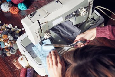 Evde retro dikiş makinesi kullanan bir kadın terzi, hobi konsepti..