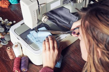 Evde retro dikiş makinesi kullanan bir kadın terzi, hobi konsepti..