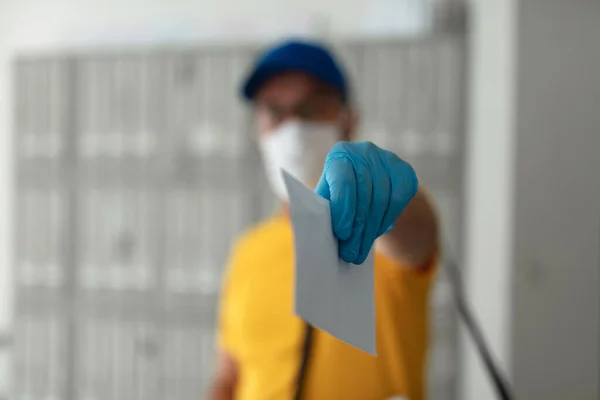 Mailman delivering mail with mail-bag and protective mask and gloves during virus pandemic.