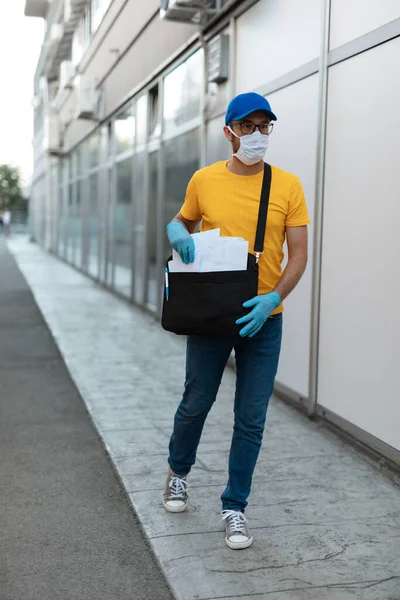 ウイルスのパンデミックの間に電子メールバッグと保護マスクと手袋を備えた郵便配達人 — ストック写真
