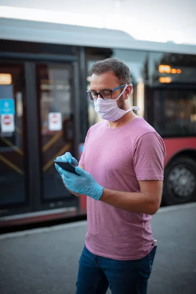 의료용 마스크를 장갑을 정류장에서 대중교통을 기다리며 스마트폰을 사용하는 — 스톡 사진