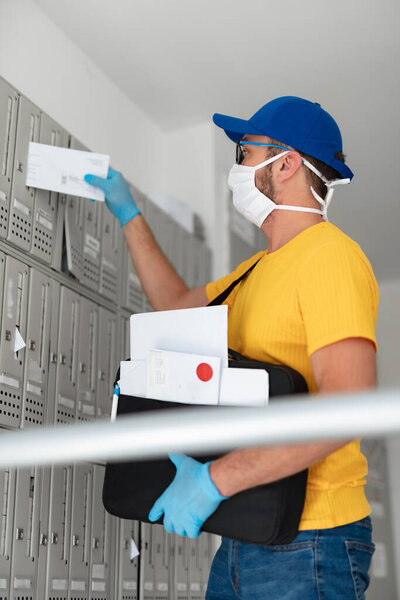 Mailman delivering mail with mail-bag and protective mask and gloves during virus pandemic.