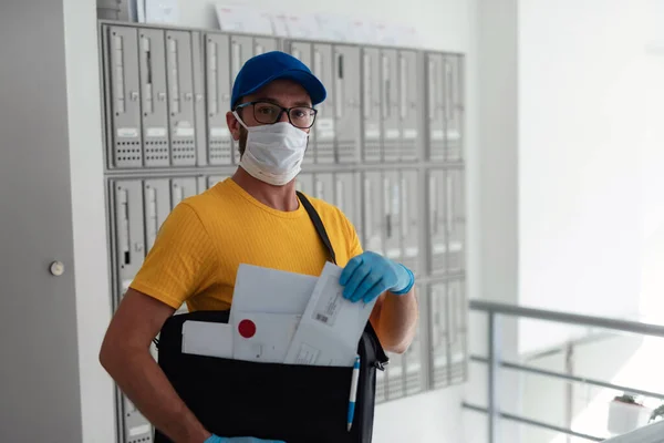 Mailman delivering mail with mail-bag and protective mask and gloves during virus pandemic.