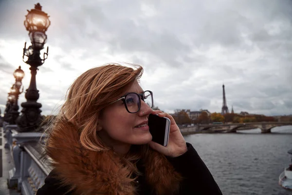 Paris geçmişi olan cep telefonu kullanan bir kız, Seine nehri ve Eyfel kulesi..