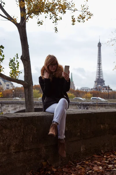 Paris geçmişi olan cep telefonu kullanan bir kız, Seine nehri ve Eyfel kulesi..