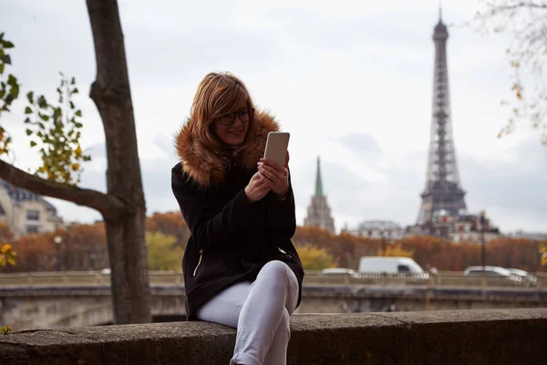パリ市内の背景を持つ携帯電話を使用して女の子 セーヌ川とエッフェル塔 — ストック写真