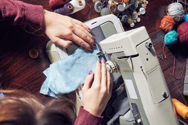 Woman tailor using retro sewing machine at home, hobby concept.