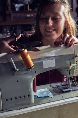 Evde retro dikiş makinesi kullanan bir kadın terzi, hobi konsepti..