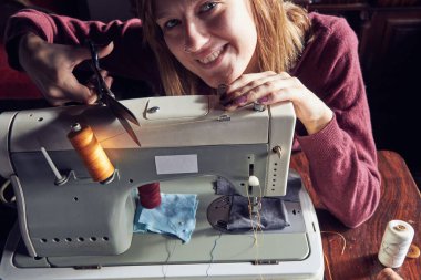 Evde retro dikiş makinesi kullanan bir kadın terzi, hobi konsepti..