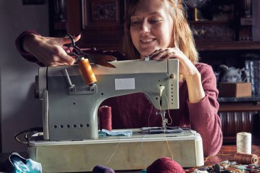 Evde retro dikiş makinesi kullanan bir kadın terzi, hobi konsepti..
