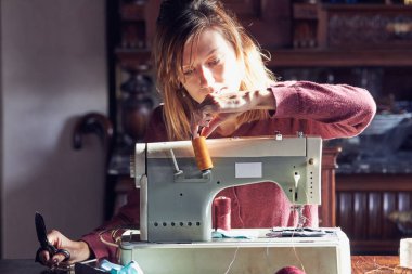 Evde retro dikiş makinesi kullanan bir kadın terzi, hobi konsepti..