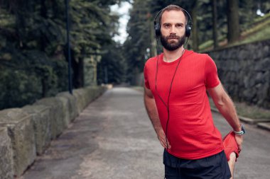 Sportif yetişkin adam parkta koşup egzersiz yaptıktan sonra duraklıyor..