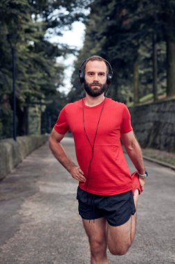 Sportif yetişkin adam parkta koşup egzersiz yaptıktan sonra duraklıyor..