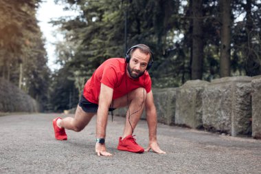 Sportif yetişkin adam parkta koşup egzersiz yaptıktan sonra duraklıyor..