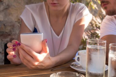 Arkadaşlar bir kafede sabah-akşam kahvesini içip modern akıllı telefon kullanıyorlar..