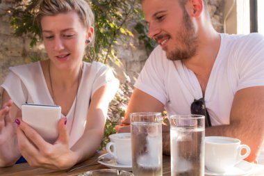 Arkadaşlar bir kafede sabah-akşam kahvesini içip modern akıllı telefon kullanıyorlar..