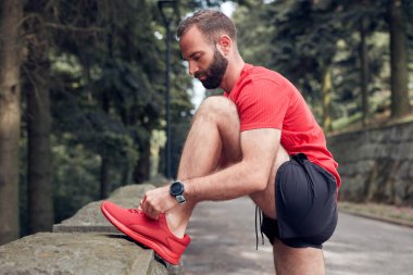 Parkta koşu ayakkabısı bağlayan sporcu..