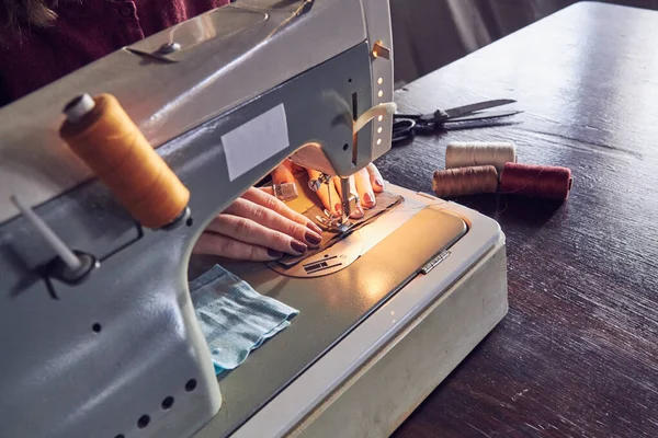 Woman tailor using retro sewing machine at home, hobby concept.