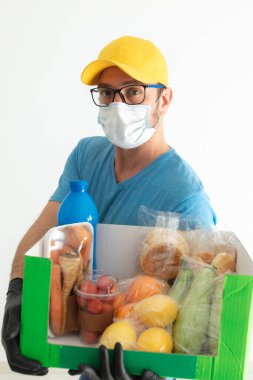Koruyucu maskeli teslimatçı. Bakkaliye kutusuyla birlikte..