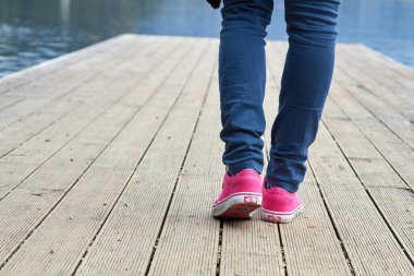 Pembe / mor tuval kumaş ayakkabılı ve kot pantolonlu kadın..
