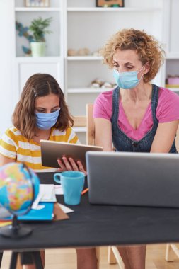 Virüsler, grip ve mevsimsel salgın zamanında özel öğretmen / koruyucu maskeli bir anneyle evde eğitim görüyor..