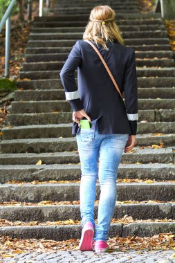 Genç beyaz kadın cebinde modern akıllı telefonu tutuyor..