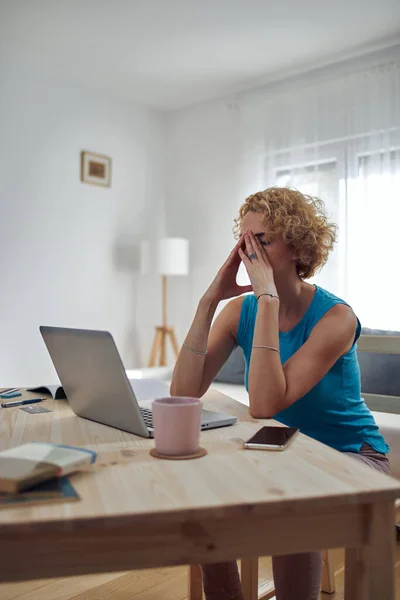 Woman working from home and being depressed, tired with headache. Modern concept and problems with freelancers.