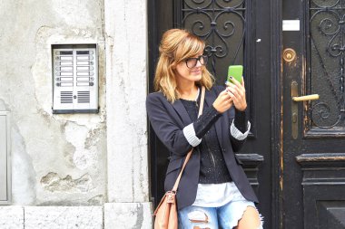 Sokakta elinde modern akıllı telefon tutan sevimli beyaz bir kadın..