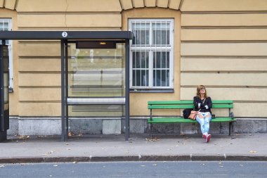 Beyaz bir kadın istasyonda toplu taşıma için bekliyor..