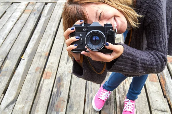 Young caucasian woman holding vintage retro camera outdoors.