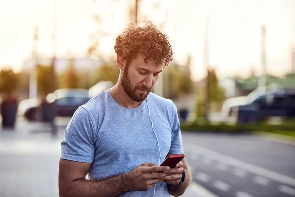 Jovem Homem Esportivo Usando Smartphone Para Ouvir Música Enquanto Exercita — Fotografia de Stock