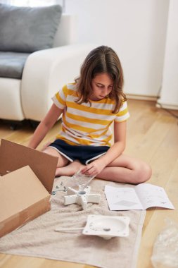 Küçük kız yeni bir evde mobilya montajı yapıyor. Yeni bir eve taşınıyor..