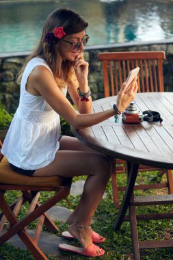 Beyaz kadın yaz mevsiminde bahçe avlusunda cep telefonu kullanıyor..