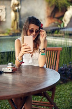 Beyaz kadın yaz mevsiminde bahçe avlusunda cep telefonu kullanıyor..