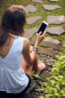 Doğu bahçesinde modern akıllı telefon kullanan beyaz bir kadın..