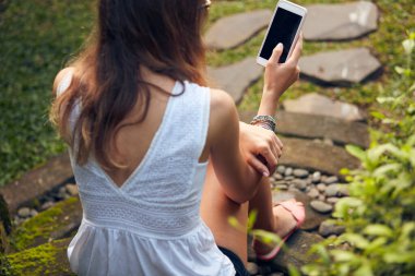 Doğu bahçesinde modern akıllı telefon kullanan beyaz bir kadın..