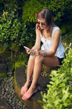 Doğu bahçesinde modern akıllı telefon kullanan beyaz bir kadın..