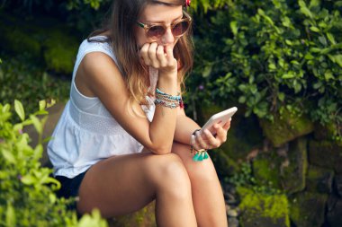 Doğu bahçesinde modern akıllı telefon kullanan beyaz bir kadın..