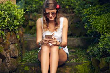 Doğu bahçesinde modern akıllı telefon kullanan beyaz bir kadın..