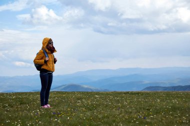 Büyük bir çayırda ve dağ manzaralı bir kadın..