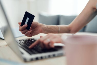 Kredi kartı tutan ve modern bilgisayarla online alışveriş yapan bir kadın..
