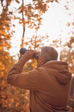 Kuşları ve diğer hayvanları dürbünle gözlemleyen amatör kuş gözlemcisi..